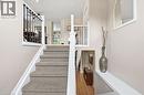 Carpeted staircase with white risers, black metal balusters, and wood-finish flooring - 94 Kent Road, Brantford, ON 