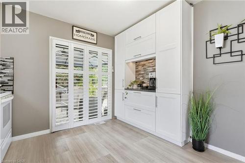 White cabinetry with integrated appliances, wood-finish flooring, and a stone-tiled backsplash - 94 Kent Road, Brantford, ON 