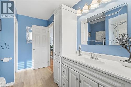 White shaker-style cabinetry with ample storage, integrated single-basin sink, and a mounted mirror with overhead lighting - 94 Kent Road, Brantford, ON 