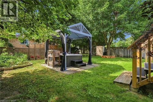 Expansive backyard featuring a hot tub with a gazebo, established trees, and a wooden fence - 94 Kent Road, Brantford, ON 