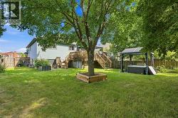 Expansive green lawn with mature trees, raised garden beds, and a multi-level wood deck - 