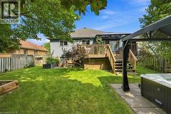 Expansive backyard featuring a manicured lawn, a two-tier wood deck, a covered patio area, and a built-in hot tub - 