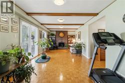 Parquet wood flooring, exposed ceiling beams, brick-clad fireplace, built-in shelving, and sliding glass doors - 