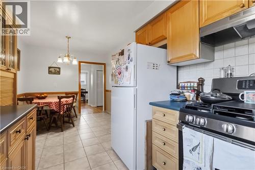 Kitchen featuring wood-finish cabinetry, tile flooring, and a stainless steel gas range with a coordinating range hood - 152 Hilda Avenue, North York, ON 