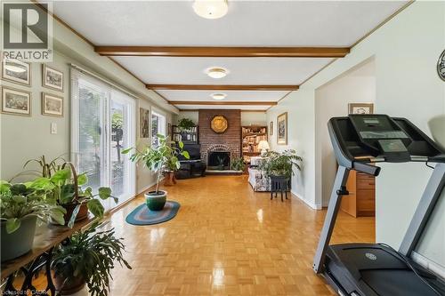 Parquet wood flooring, exposed ceiling beams, brick-clad fireplace, built-in shelving, and sliding glass doors - 152 Hilda Avenue, North York, ON 