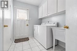 White tile flooring, utility sink, white upper cabinetry, and white appliances - 