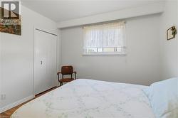 White walls with a single window, bi-fold closet doors, and wood-finish flooring - 