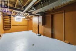 Finished basement space featuring exposed ceiling joists, built-in shelving, a single window, and painted concrete flooring - 