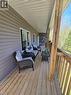 Expansive covered porch featuring a wood-plank floor, natural wood support posts, and a stone accent wall - 2516 Irish Line, Coldwater, ON 