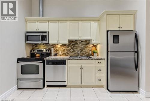 Stainless steel appliances, mosaic tile backsplash, light-colored cabinetry, granite-finish countertops, and tiled flooring - 25 Concession Street Unit# 110, Cambridge, ON 