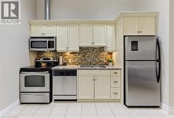 Stainless steel appliances, mosaic tile backsplash, light-colored cabinetry, granite-finish countertops, and tiled flooring - 