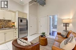 Kitchenette with cream cabinetry, stainless steel refrigerator, and tiled backsplash - 