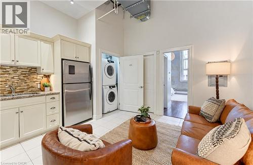 Full-height cabinetry with stainless steel appliances, stacked laundry appliances, and tile flooring - 25 Concession Street Unit# 110, Cambridge, ON 