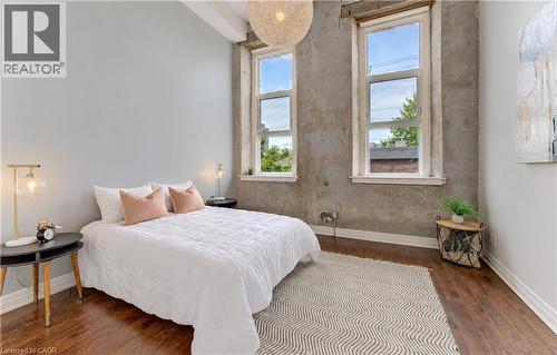 Hardwood flooring, painted walls, exposed concrete wall, two windows, and a ceiling-mounted light fixture - 25 Concession Street Unit# 110, Cambridge, ON 
