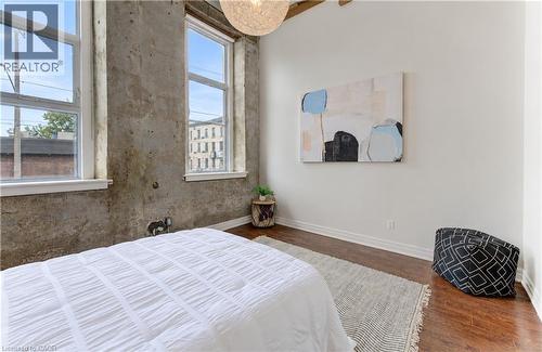Exposed concrete wall, wood-finish flooring, high ceilings, large windows, and a built-in overhead light fixture - 25 Concession Street Unit# 110, Cambridge, ON 