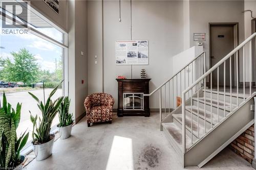 Full-height windows, concrete flooring, exposed brick detailing, and a metal staircase with railing - 25 Concession Street Unit# 110, Cambridge, ON 