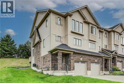 Multi-level townhouse with brick and siding exterior, private garage, and sloped grassy area - 226 Maitland Street, Kitchener, ON 