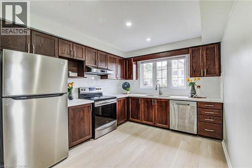 Kitchen featuring wood-finish cabinetry, stainless steel appliances, light-toned flooring, white subway tile backsplash, and recessed lighting - 226 Maitland Street, Kitchener, ON 