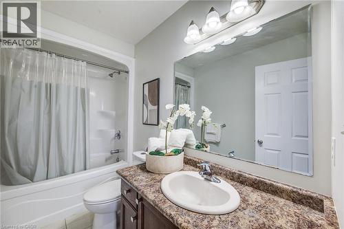Bathroom featuring a bathtub with shower, integrated vanity with an oval sink, textured countertop, and an expansive wall mirror - 226 Maitland Street, Kitchener, ON 