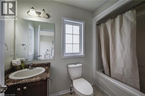 Bathroom featuring a single vanity with an oval sink, a wall-mounted mirror, a window with grid patterns, and a tub with a shower - 226 Maitland Street, Kitchener, ON 