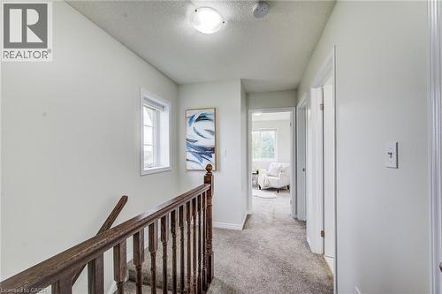 Upper hallway with carpeting, natural wood banister, and a white-framed window - 226 Maitland Street, Kitchener, ON 