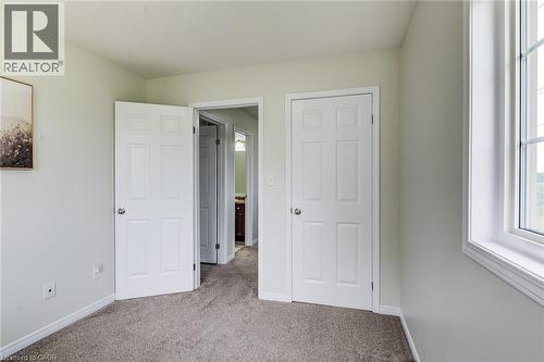 Window with white trim, light-toned carpeting, and a six-panel door - 226 Maitland Street, Kitchener, ON 
