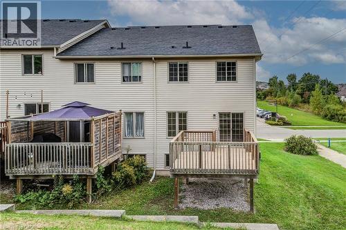 Two-story property with light-colored siding, a dark shingle roof, two wooden decks, and a ground-level patio - 226 Maitland Street, Kitchener, ON 