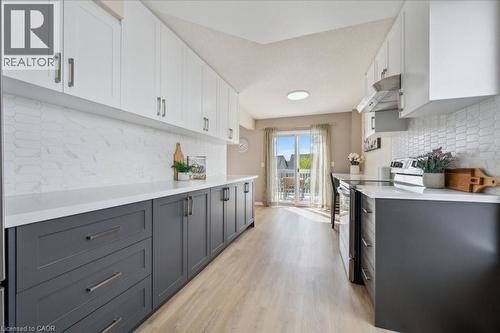 Kitchen featuring decorative backsplash, stainless steel stove, gray cabinets, and white cabinetry - 47 Mccurdy Road, Guelph, ON 