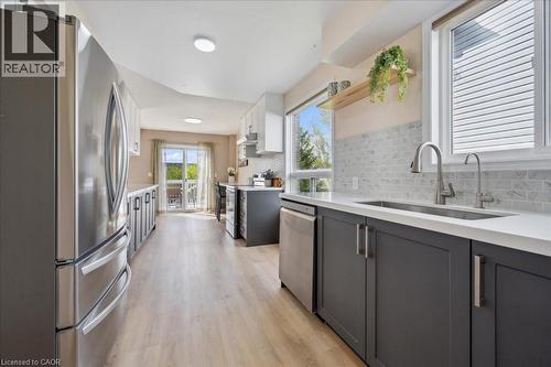 Kitchen with appliances with stainless steel finishes, decorative backsplash, light wood-type flooring, and light stone counters - 47 Mccurdy Road, Guelph, ON 