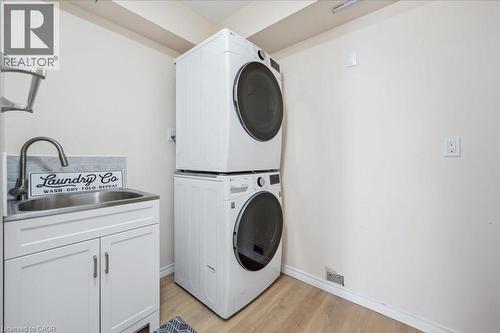 Laundry room featuring light wood-style flooring, stacked washing machine and dryer, and cabinet space - 47 Mccurdy Road, Guelph, ON 