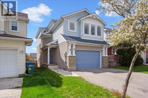View of front of property with an attached garage, brick siding, asphalt driveway, and a front yard - 47 Mccurdy Road, Guelph, ON 
