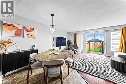 Hardwood flooring, sliding glass door, modern chandelier, tile flooring, and window blinds - 245 Red Clover Court, Kitchener, ON 