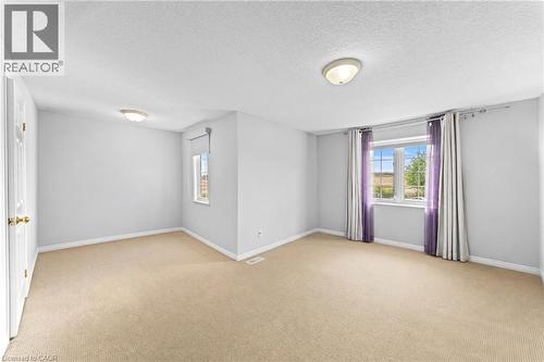 Carpeted flooring, multiple windows, interior door with brass hardware, and ceiling-mounted light fixtures - 245 Red Clover Court, Kitchener, ON 