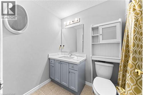 Vanity with a white countertop and gray cabinetry, white toilet, and white over-the-toilet shelving unit - 245 Red Clover Court, Kitchener, ON 