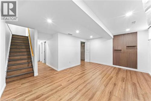 Recessed lighting, wood-finish flooring, wood slatted accent wall with integrated shelving, white walls, wood staircase - 245 Red Clover Court, Kitchener, ON 