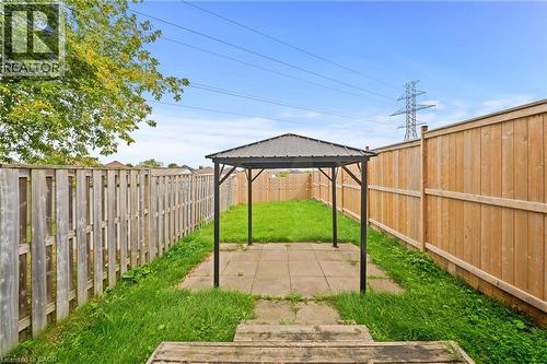 Expansive backyard featuring a central paver patio, a freestanding gazebo with a metal roof, and surrounding grass areas - 245 Red Clover Court, Kitchener, ON 