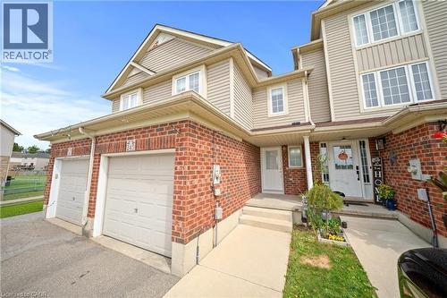 Brick and siding exterior with multiple windows, two garage doors, a concrete walkway, and a covered entry - 245 Red Clover Court, Kitchener, ON 
