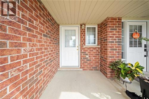 Brick exterior, white entry door with glass insert, white window with grid, covered entryway, and concrete porch - 245 Red Clover Court, Kitchener, ON 