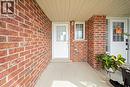 Brick exterior, white entry door with glass insert, white window with grid, covered entryway, and concrete porch - 245 Red Clover Court, Kitchener, ON 