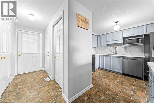 Kitchen featuring light blue cabinetry, white countertops, stainless steel appliances, and a white backsplash with gray veining - 245 Red Clover Court, Kitchener, ON 