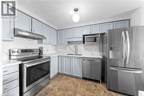 Kitchen featuring stainless steel appliances, light-colored cabinetry, white countertops, and a white backsplash with gray veining - 245 Red Clover Court, Kitchener, ON 