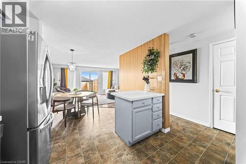 Tile flooring, stainless steel refrigerator, kitchen island with storage, wood slat accent wall, sliding glass doors - 245 Red Clover Court, Kitchener, ON 
