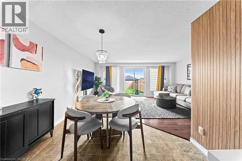 Open living space featuring wood-finish flooring, light-toned wall paneling, and sliding glass doors - 245 Red Clover Court, Kitchener, ON 