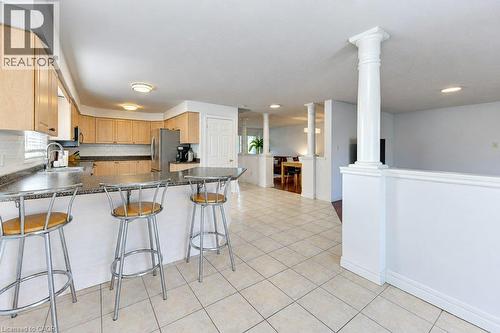 Kitchen featuring light wood-finish cabinetry, dark countertop, tile flooring, and integrated stainless steel appliances - 88 Decaro Crescent, Cambridge, ON 