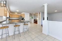 Kitchen featuring light wood-finish cabinetry, dark countertop, tile flooring, and integrated stainless steel appliances - 