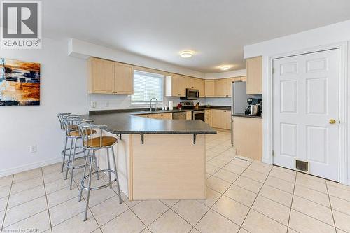 Kitchen featuring light wood-finish cabinetry, dark countertops, and stainless steel appliances - 88 Decaro Crescent, Cambridge, ON 