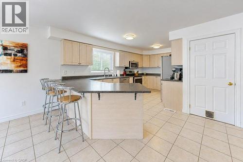 Kitchen featuring light wood-finish cabinetry, solid surface countertops, stainless steel appliances, and tiled flooring - 88 Decaro Crescent, Cambridge, ON 