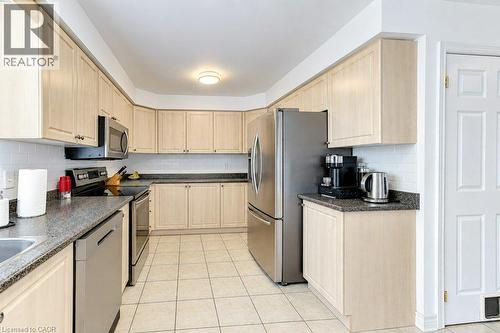 Light-toned cabinetry with dark countertops, stainless steel appliances, white subway tile backsplash, and light-colored floor tiling - 88 Decaro Crescent, Cambridge, ON 