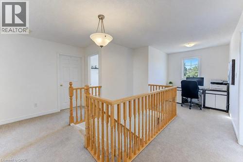 Open landing featuring light wood railings, a suspended ceiling fixture, and carpeted flooring - 88 Decaro Crescent, Cambridge, ON 