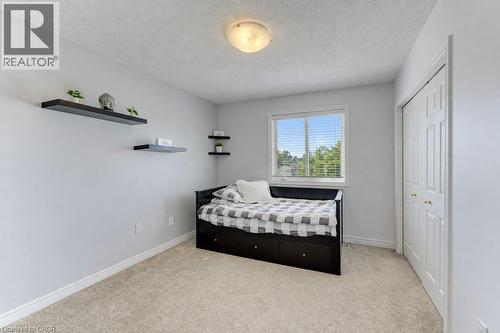 Textured carpet flooring, white painted walls, a double-pane window with blinds, and a white two-panel closet door - 88 Decaro Crescent, Cambridge, ON 